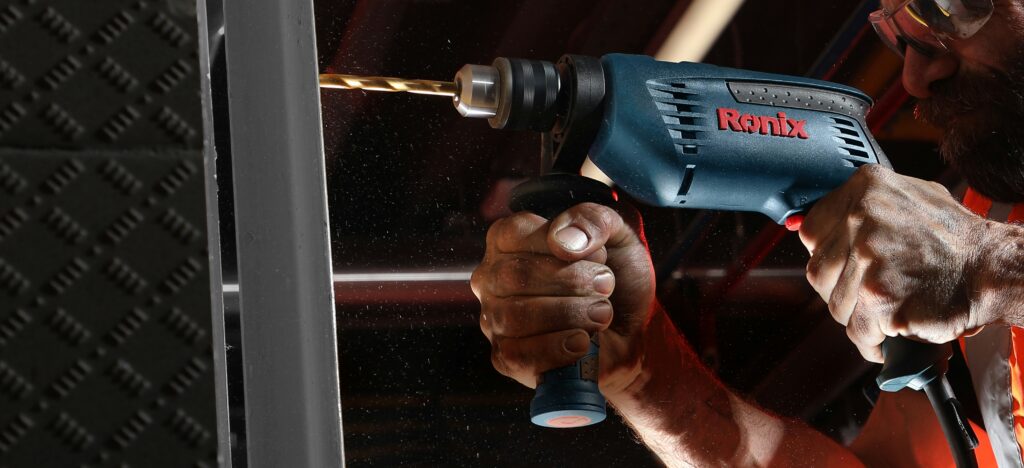 Hammer Drill A hammer drill with an attached side handle is drilling through the material.